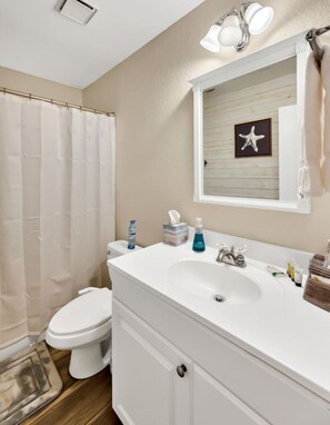 A bathroom with a white sink, toilet, and shower curtain.