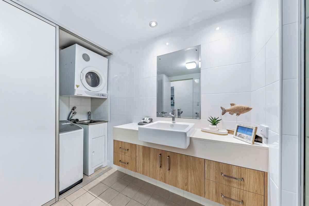 A modern bathroom with a built-in washing machine, a sink, and a mirror.