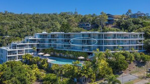 Un hotel a più piani con piscina, immerso nel verde e circondato da colline.