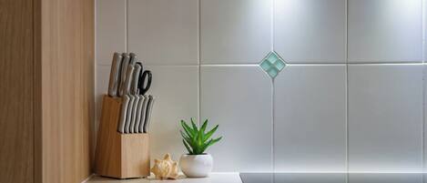 A kitchen counter with a knife block, a potted plant, and a decorative item.