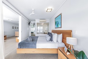 Ein modernes Schlafzimmer mit einem hölzernen Bett, einem Nachttisch mit Lampe und einem großen Fenster.