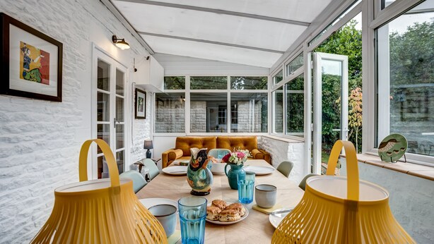 A dining area with a table set for four, featuring yellow lamps, blue glassware, and a decorative owl centerpiece.
