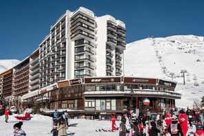 A multi-story hotel with balconies, ski resort signage, and a ski lift in the background.