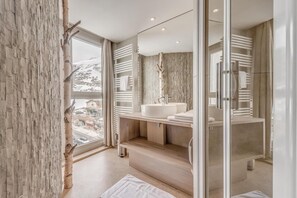 A modern bathroom with a large window, a white sink, and a glass shower enclosure. - 10m from ski slopes, 4th floor, view mountain, tv, ski locker, 40m², Tignes (Tignes)
