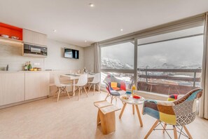 A modern kitchen with a dining area, a TV, and a large window with a snowy mountain view. - 10m from ski slopes, 4th floor, view mountain, tv, ski locker, 40m², Tignes (Tignes)