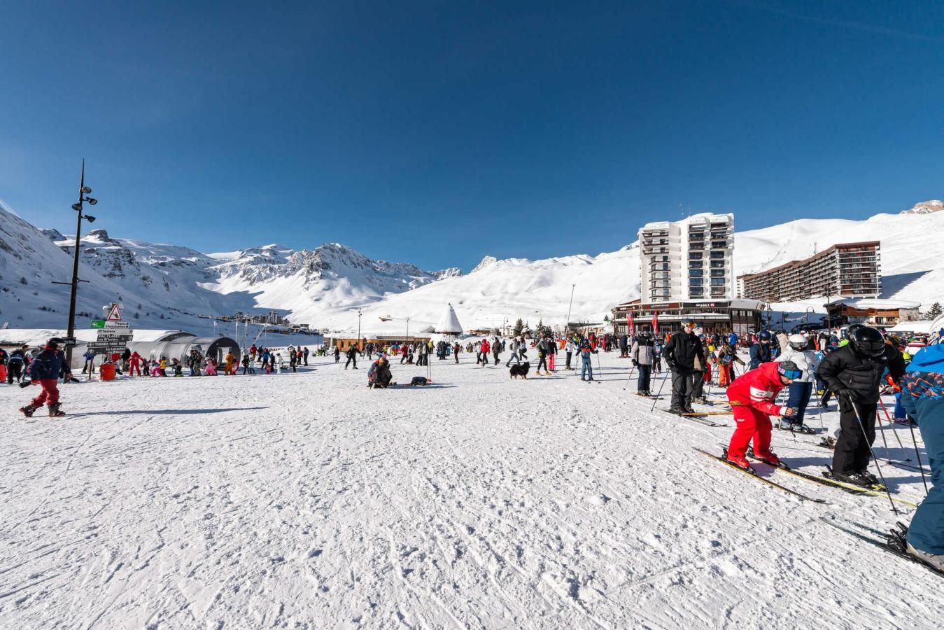 Estació d'esquí amb una zona ampla oberta, pistes d'esquí i edificis al fons.