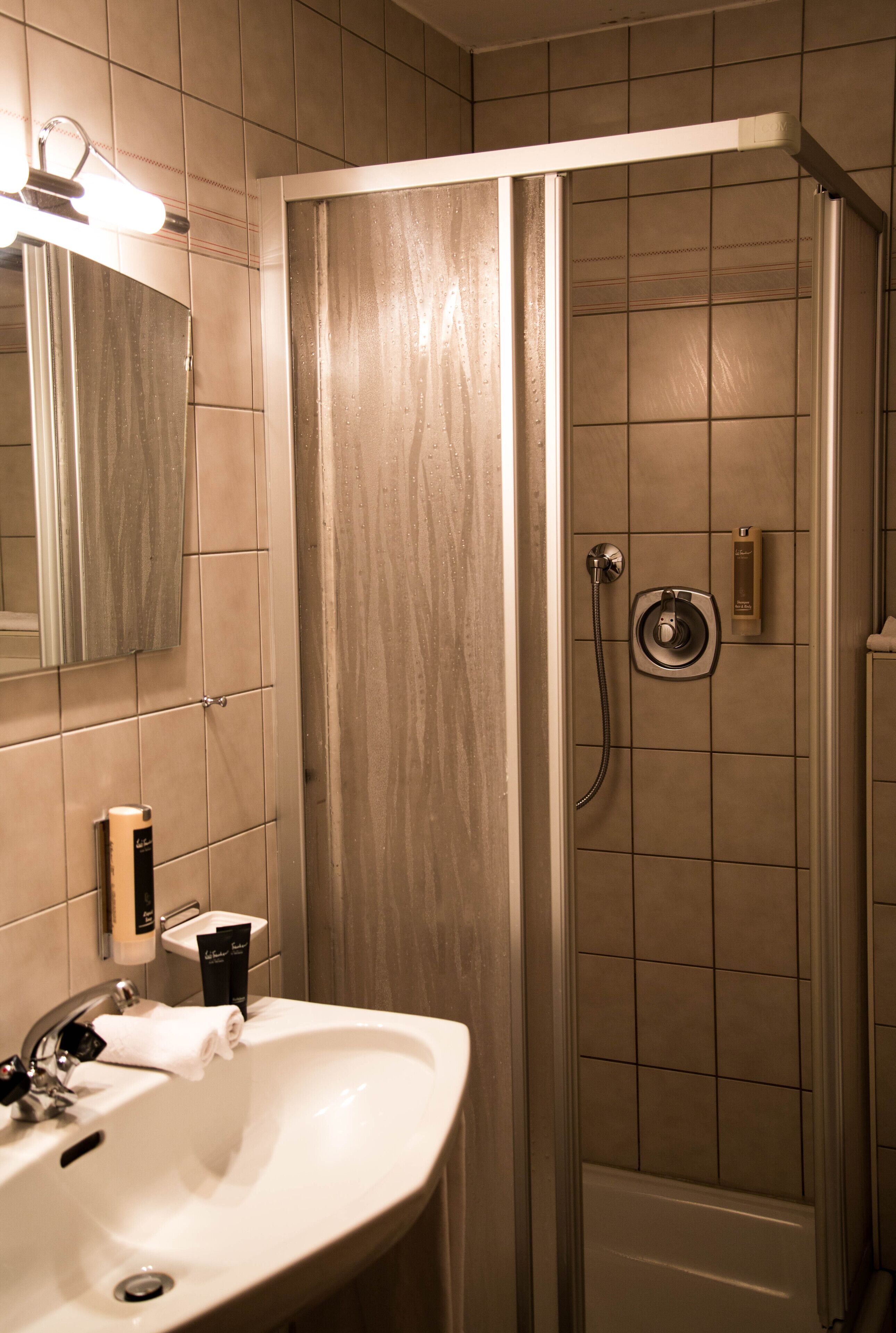 Une salle de bain avec un lavabo, un miroir et une douche.