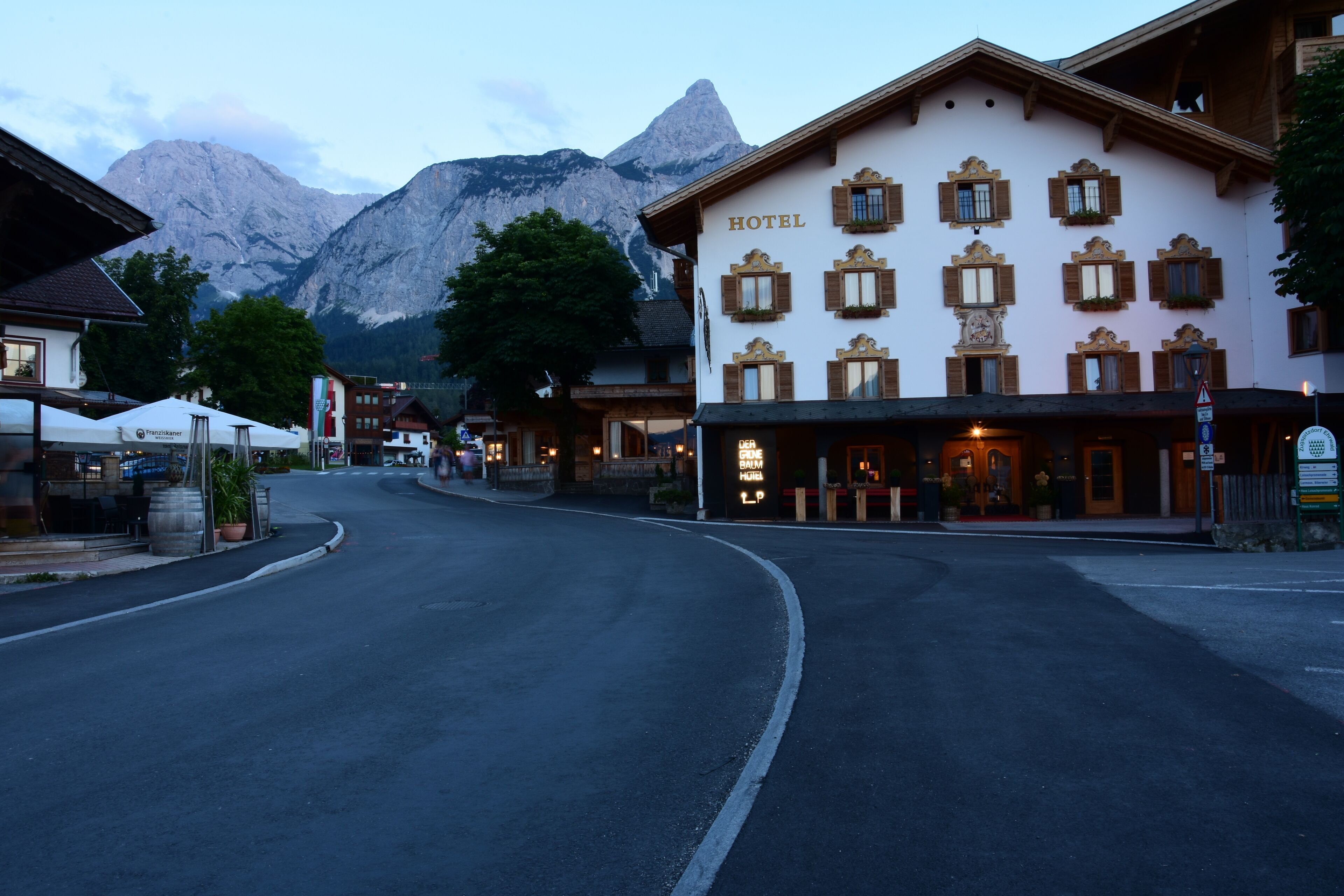 A hotel with a mountain view, a sign for a local brewery, and a clear road in front.