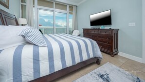 Una camera da letto con un letto grande, un comò, una televisione e un balcone con vista.