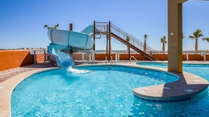 A swimming pool with a water slide, a staircase, and palm trees in the background. - Phoenix Gulf Shores 1602-1 1 Bedroom Condo (Gulf Shores)