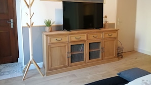 Une pièce comprenant un meuble en bois, un téléviseur à écran plat et un porte-manteau.