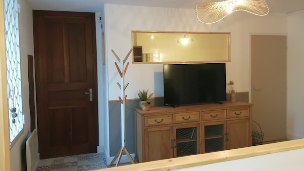 Une pièce comprenant un meuble en bois, un téléviseur à écran plat, un miroir et un luminaire fixé au plafond.