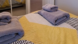Ein ordentlich eingerichtetes Schlafzimmer mit einem Bett, einem Spiegel und einer Tür zu einem weiteren Raum.