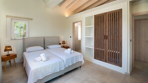 A bedroom with a large bed, bedside tables, a wooden wardrobe, and a window. - Above Blu Villa - Two Bedroom Villa, Sleeps 4 (Gaios)