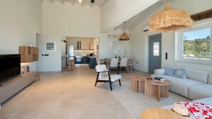 A spacious living area with a sofa, coffee tables, and a TV. A kitchen is visible in the background. - Above Blu Villa - Two Bedroom Villa, Sleeps 4 (Gaios)