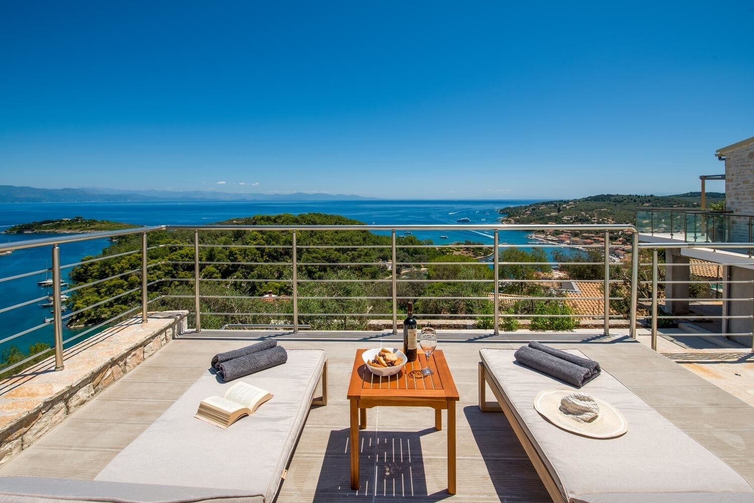 Eine Terrasse mit Tisch, Stühlen und Blick auf das Meer und die Landschaft.