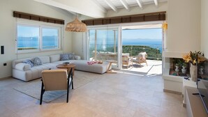 A spacious living area with a sofa, a coffee table, and a balcony with a view of the sea. - Above Blu Villa - Two Bedroom Villa, Sleeps 4 (Gaios)