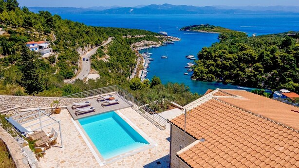 A rooftop pool with lounge chairs, a stone deck, and a view of the sea and boats. - Above Blu Villa - Two Bedroom Villa, Sleeps 4 (Gaios)