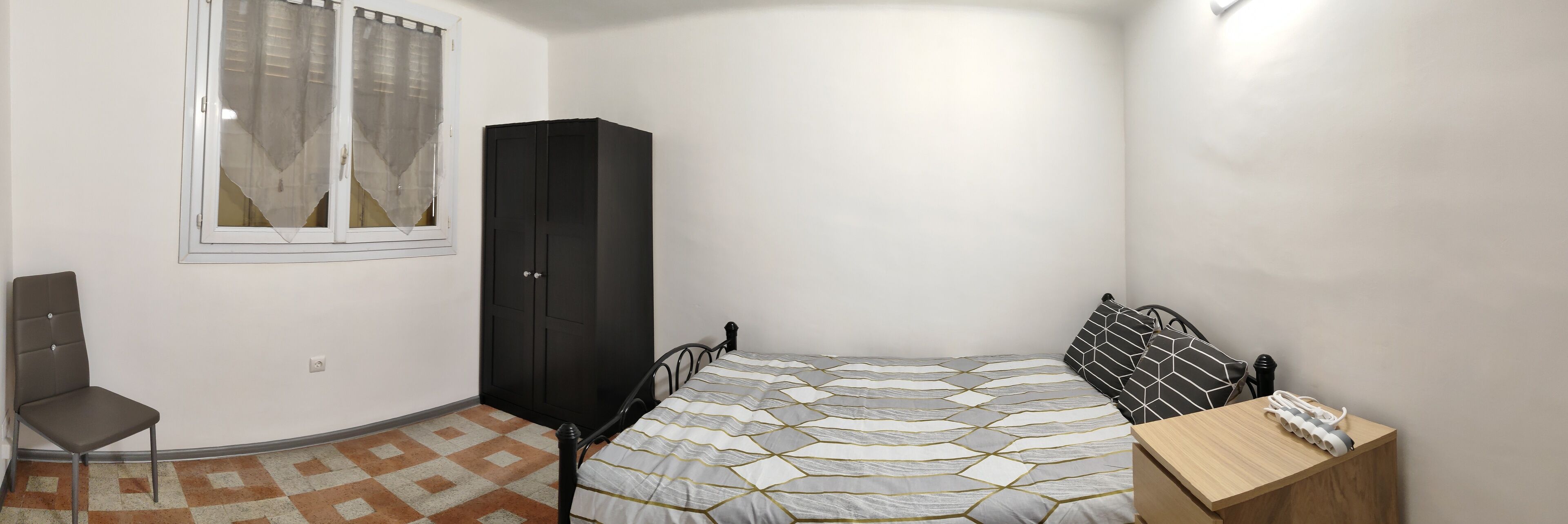 A bedroom with a bed, a chair, a wardrobe, and a desk.