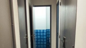Un pasillo con piso de cuadros, puertas a ambos lados y un banco acolchado azul al fondo.