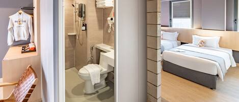 A modern hotel room with a shower, toilet, and a bed with two pillows.