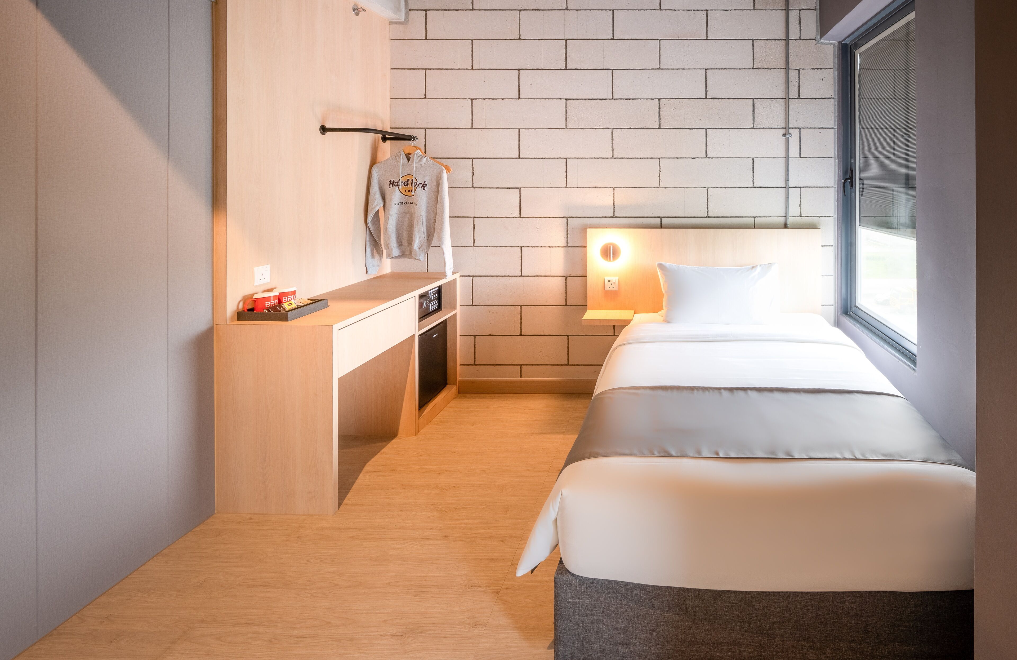 A compact hotel room with a bed, bedside table, and a small desk with a chair.