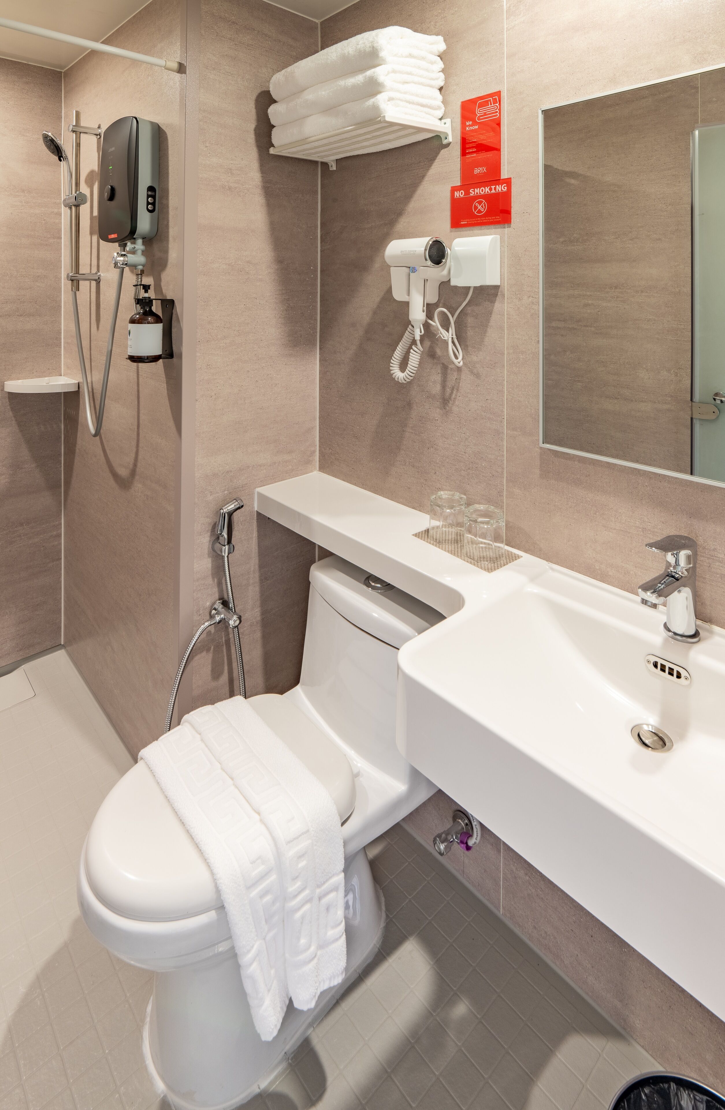A modern bathroom with a toilet, bidet, shower, and sink.