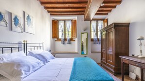 Un dormitorio con cama, armario de madera y ventana con cortinas.