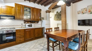 Una cocina con armarios de madera, una estufa y una mesa de comedor con cojines azules.