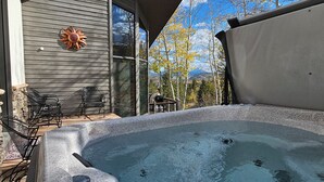 A hot tub on a patio with chairs and a sun decoration.
