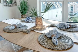 Una mesa redonda de madera con individuales tejidos, un florero de vidrio y un mantel a rayas.