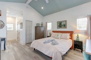 Een slaapkamer met een bed, nachtkastje, lamp, kledingkast en een schilderij aan de muur.