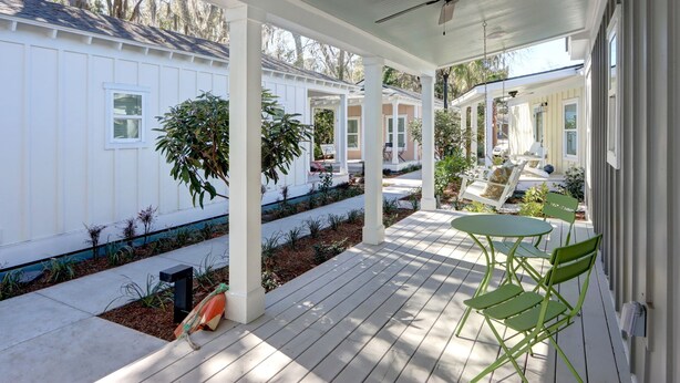 A covered porch with a ceiling fan, green chairs, and a small table. - Marsh Hen Den - 5 Min to SAV / 15 to Beach by Lucky Savanah (Thunderbolt)