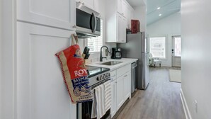 A modern kitchen with white cabinets, a stainless steel refrigerator, and a coffee maker. - Coastal Grandma Cottage - 5 min to SAV, 15 to Beach By Lucky Savannah (Thunderbolt)