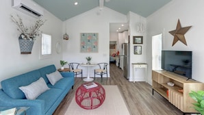 A modern living room with a blue sofa, a red round coffee table, and a TV stand with a flat-screen TV. - Coastal Grandma Cottage - 5 min to SAV, 15 to Beach By Lucky Savannah (Thunderbolt)