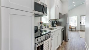 A modern kitchen with white cabinetry, a stainless steel refrigerator, a built-in oven, and a microwave.