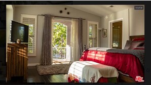 A bedroom with a bed, a TV, and a window with curtains.
