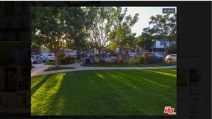 A residential property with a well-maintained lawn, a playground, and a parking area.