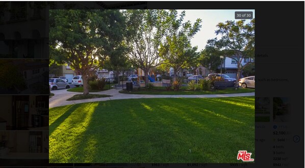 A residential property with a well-maintained lawn, a playground, and a parking area.