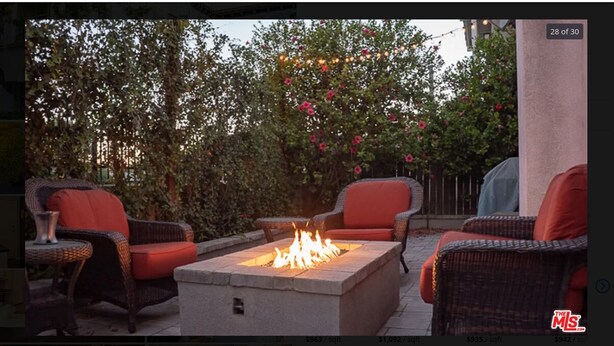 An outdoor patio area with wicker furniture and a stone fire feature.