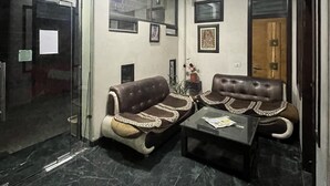 A lobby with two leather sofas, a glass partition, and a marble floor. - Hotel Tushar Residency (Mathura)