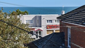 Un edificio frente al mar, con un toldo rojo y un letrero.
