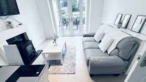 Ein modernes Wohnzimmer mit einer Couch, einem Couchtisch, einem Fernseher und einem Kamin.
