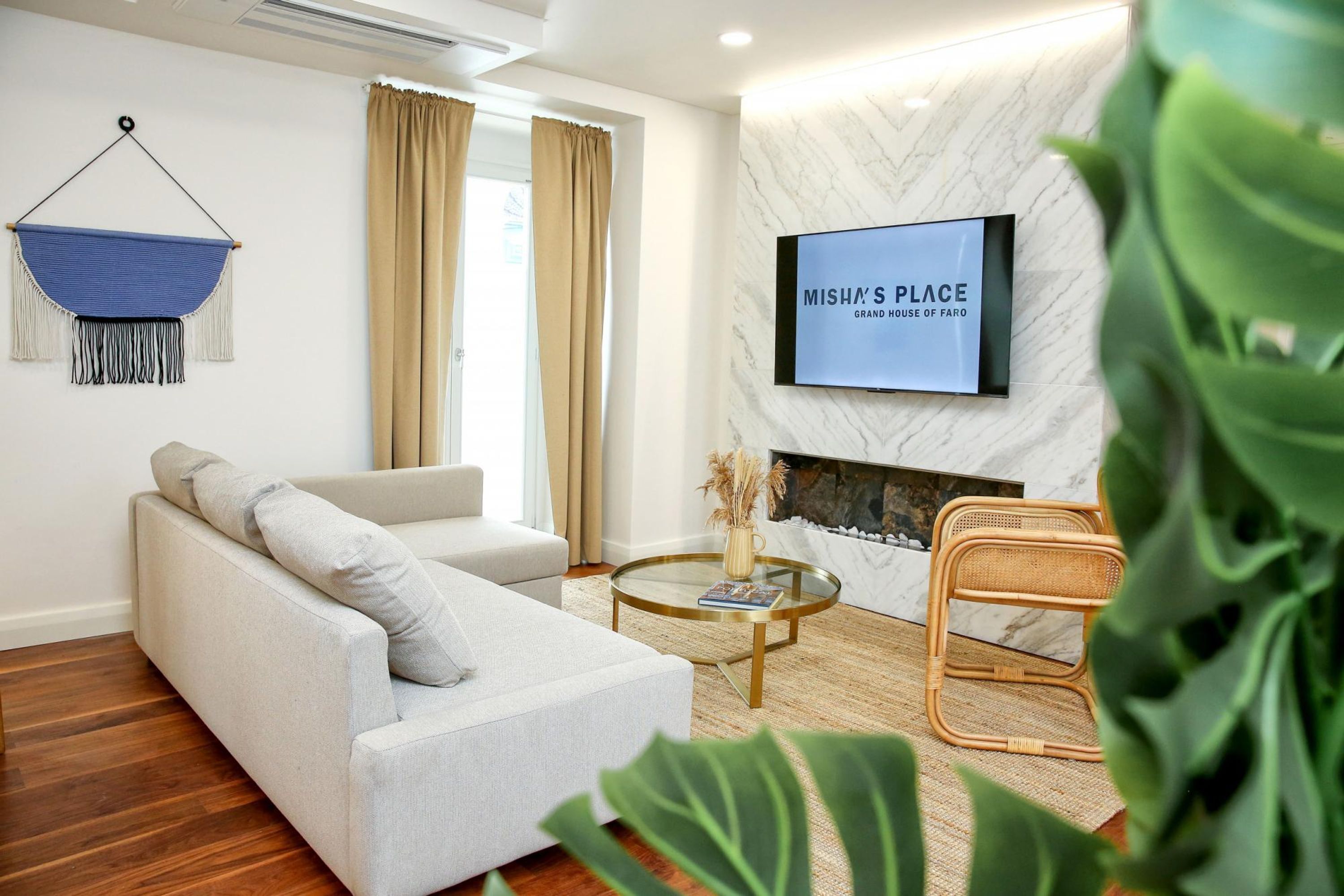 A modern living room with a sofa, a glass coffee table, and a television mounted on a marble wall.