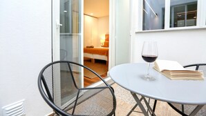 A balcony with a table, chairs, and a glass of wine. - Green Algarve Gem Spacious 2 BDR By Misha s Place (Faro)