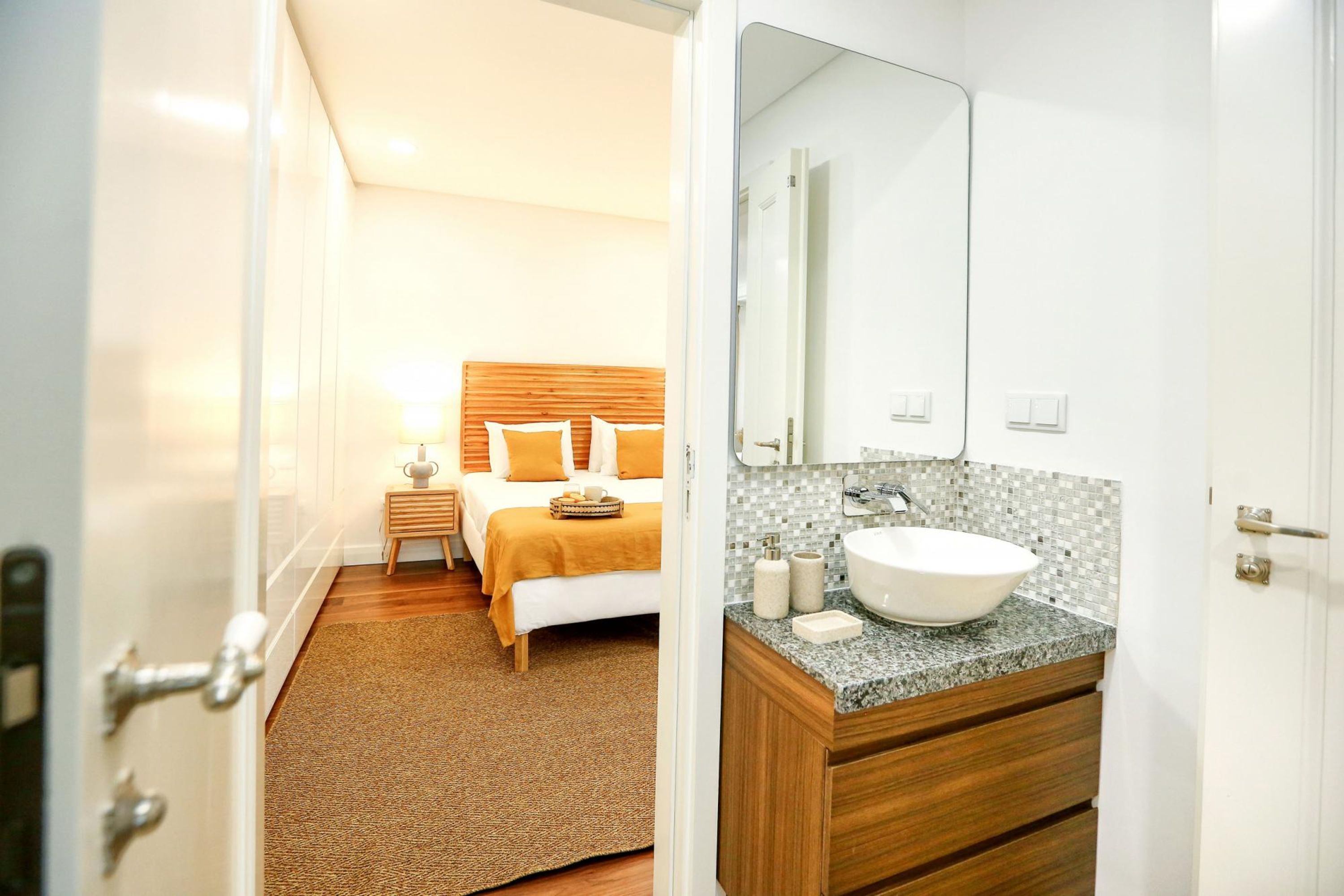 Ein Hotelzimmer mit Bett, Nachttisch, Bad mit Waschbecken und Spiegel.