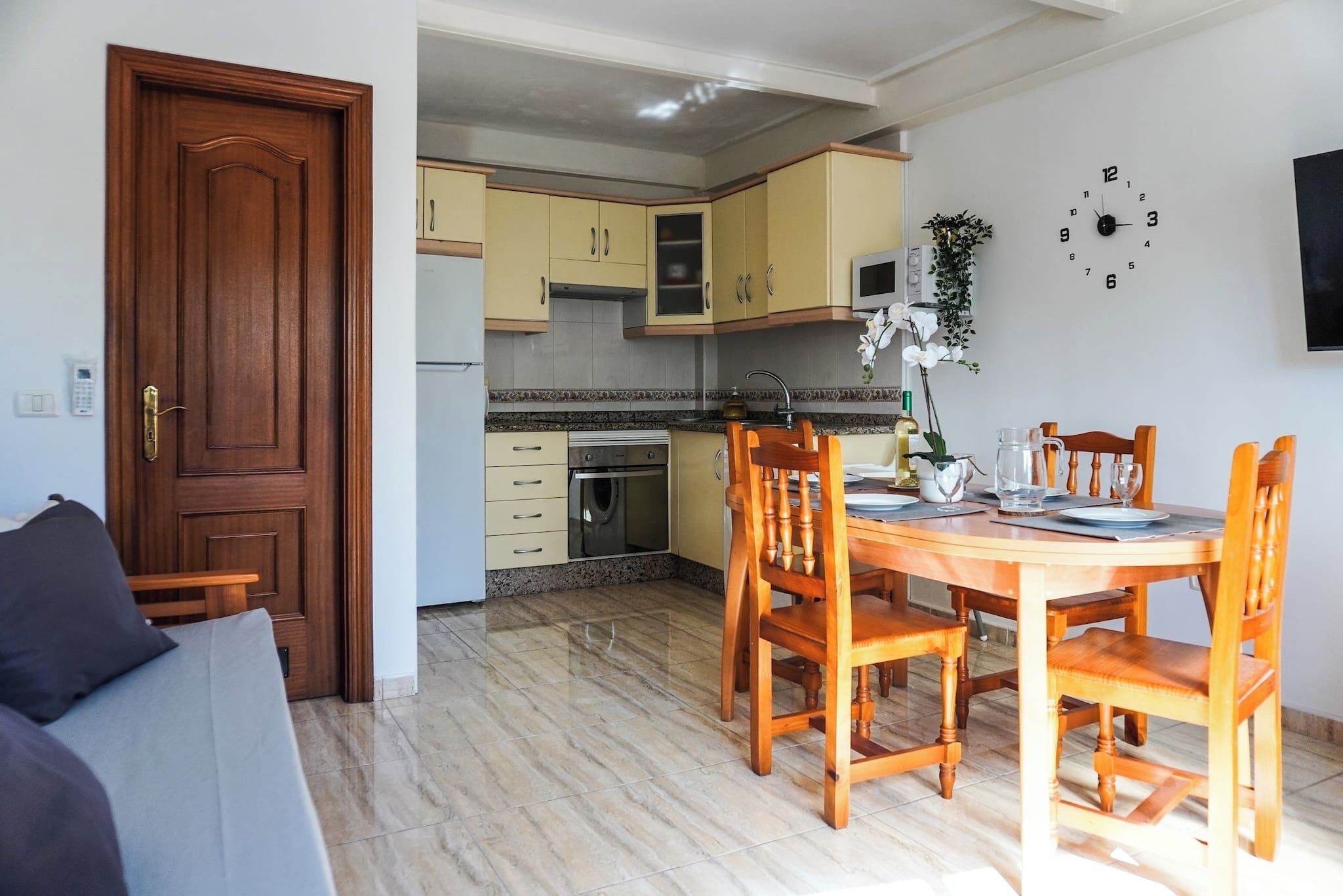 Un coin repas avec des chaises en bois, une table et une cuisine en arrière-plan.