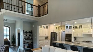 A spacious living room with a large sectional sofa, a wooden coffee table, and a staircase leading to an upper level.