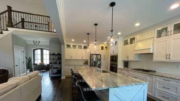 A spacious kitchen with a large island, white cabinetry, and pendant lighting.