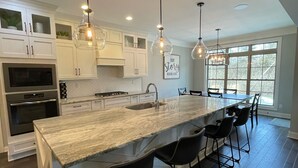 A modern kitchen with a large island, white cabinetry, and pendant lighting.